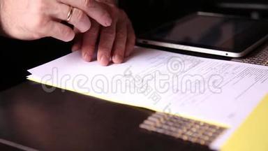 坐在办公桌前的商人签署了一份与个人电脑平板电脑比较的法案。 一个男人的特写和一个喷泉